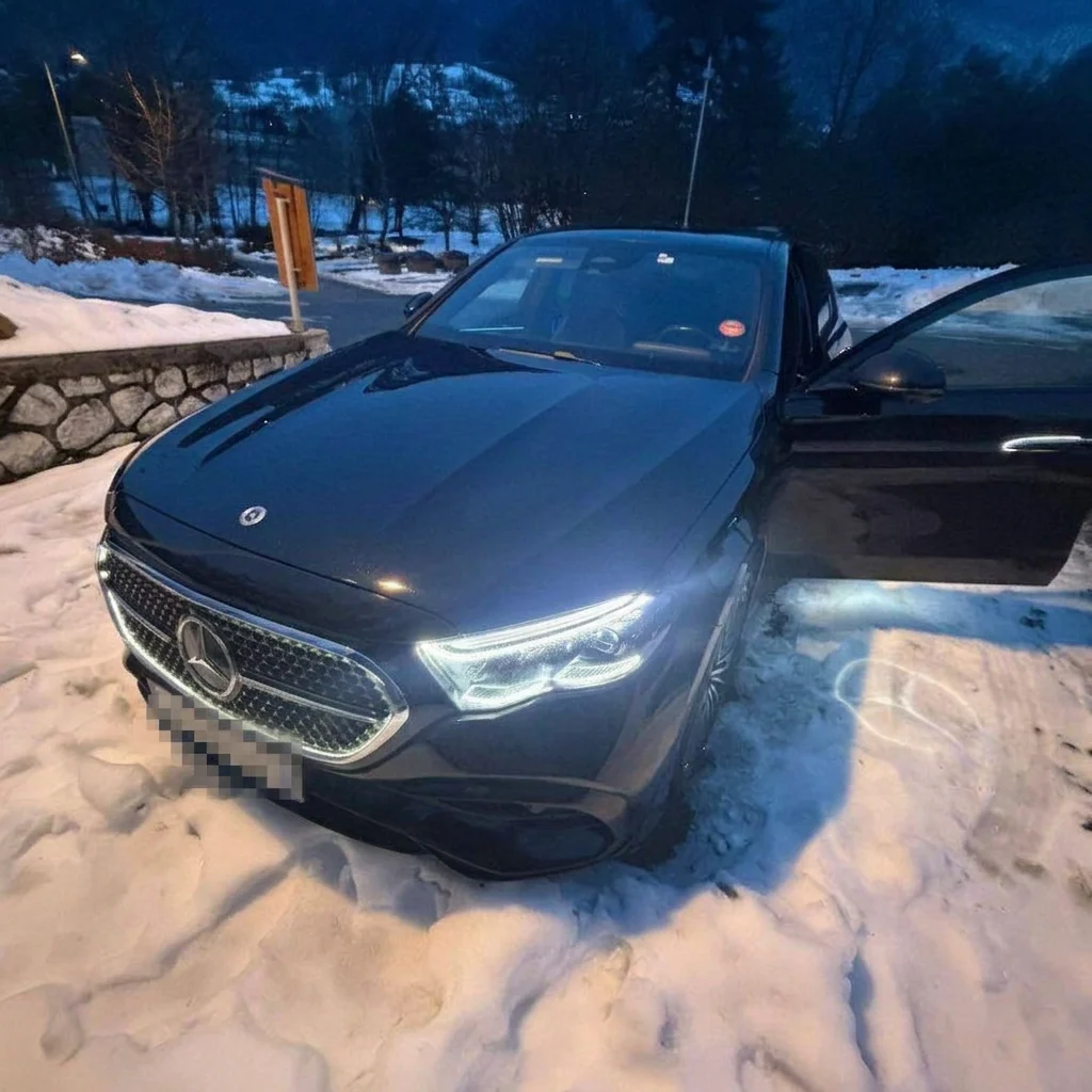 Mercedes-Benz Classe E noire phares allumés dans la neige, de nuit en montagne