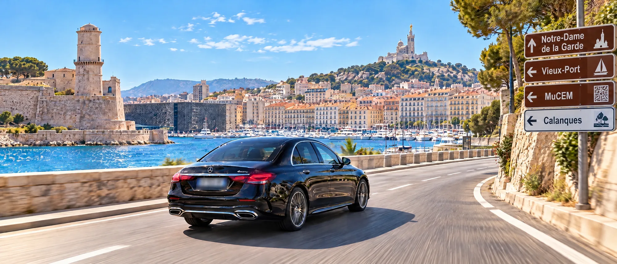 Mercedes Classe E noire roulant sur la corniche de Marseille devant le Vieux-Port et Notre-Dame de la Garde, VTC longue distance