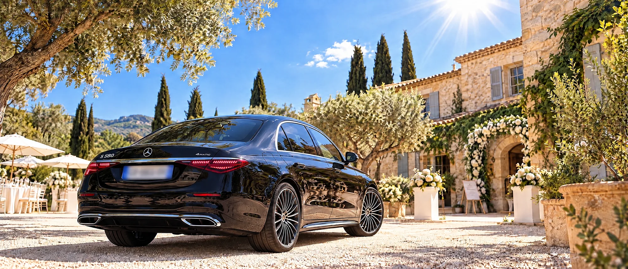 Mercedes Classe S noire vue de l’arrière devant un mas provençal décoré de fleurs blanches pour un mariage, chauffeur événements à Marseille