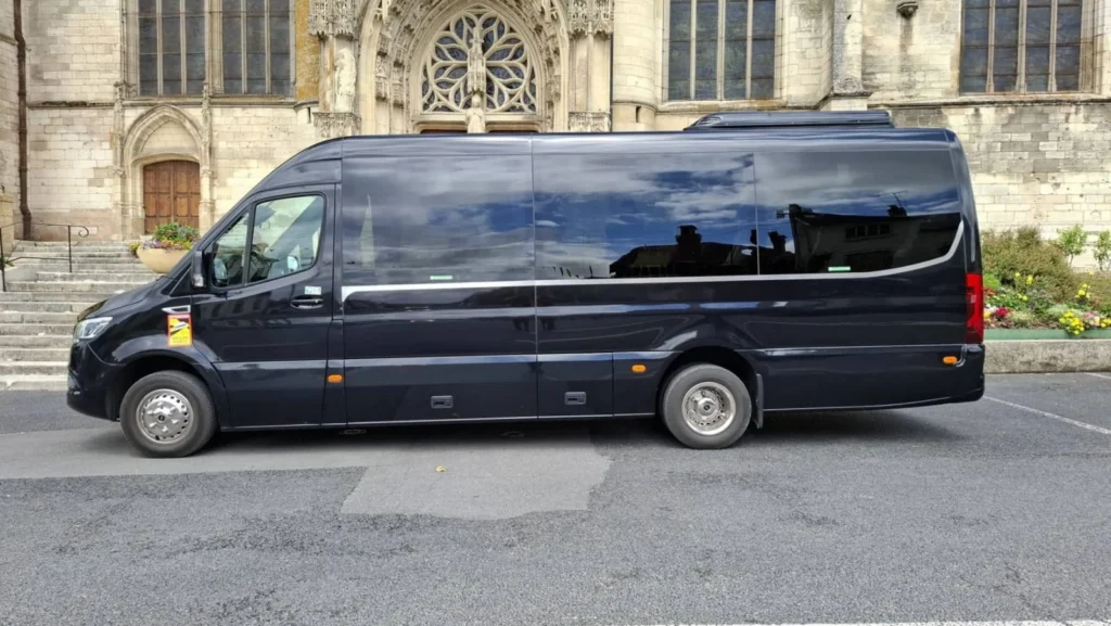 Minibus Mercedes-Benz Sprinter noir, vue de profil devant un bâtiment historique
