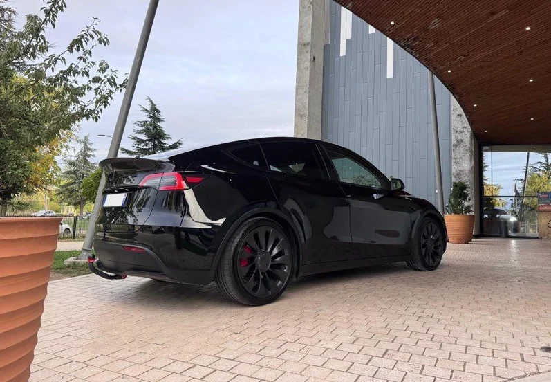 Tesla Model Y noire vue de trois quarts arrière devant un hôtel